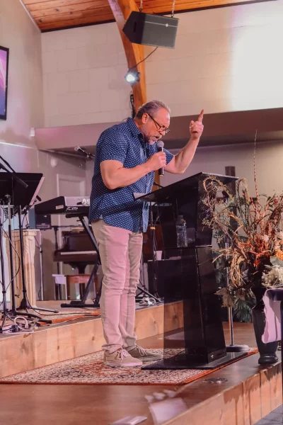 Pastor David Darst preaching from the Bible with passion during a church service.