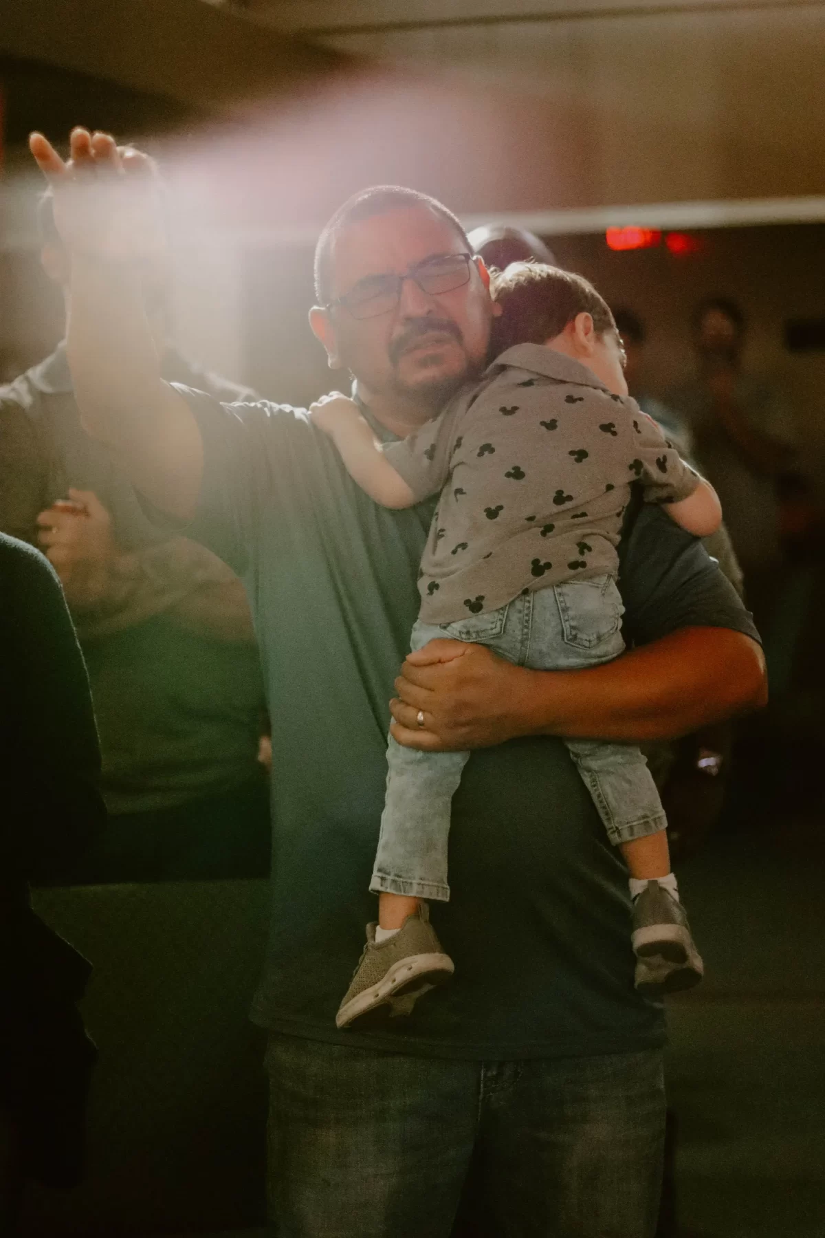 A man holding a child and lifting his hand in worship at Trinity Church Palestine, Texas.