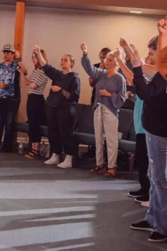People lifting their hands in worship and singing at Trinity Church Palestine, Texas.